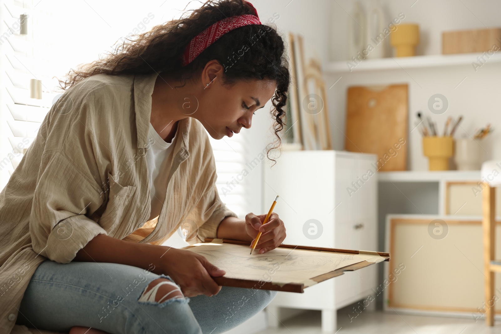 Photo of Beautiful woman drawing portrait with pencil in studio