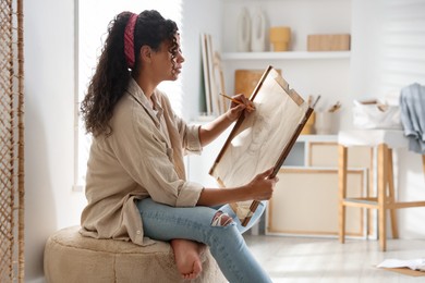 Beautiful woman drawing portrait with pencil in studio