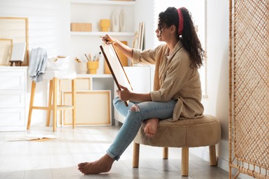 Beautiful woman drawing picture with pencil in studio