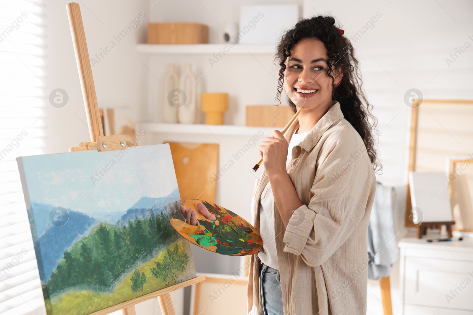 Photo of Smiling woman drawing beautiful landscape in studio