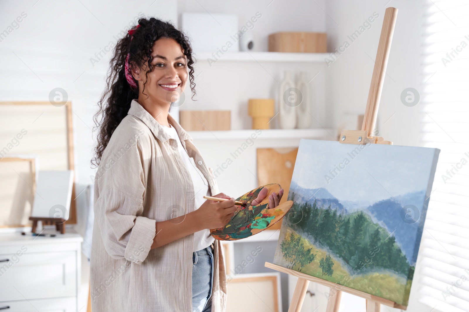 Photo of Smiling woman drawing beautiful landscape in studio