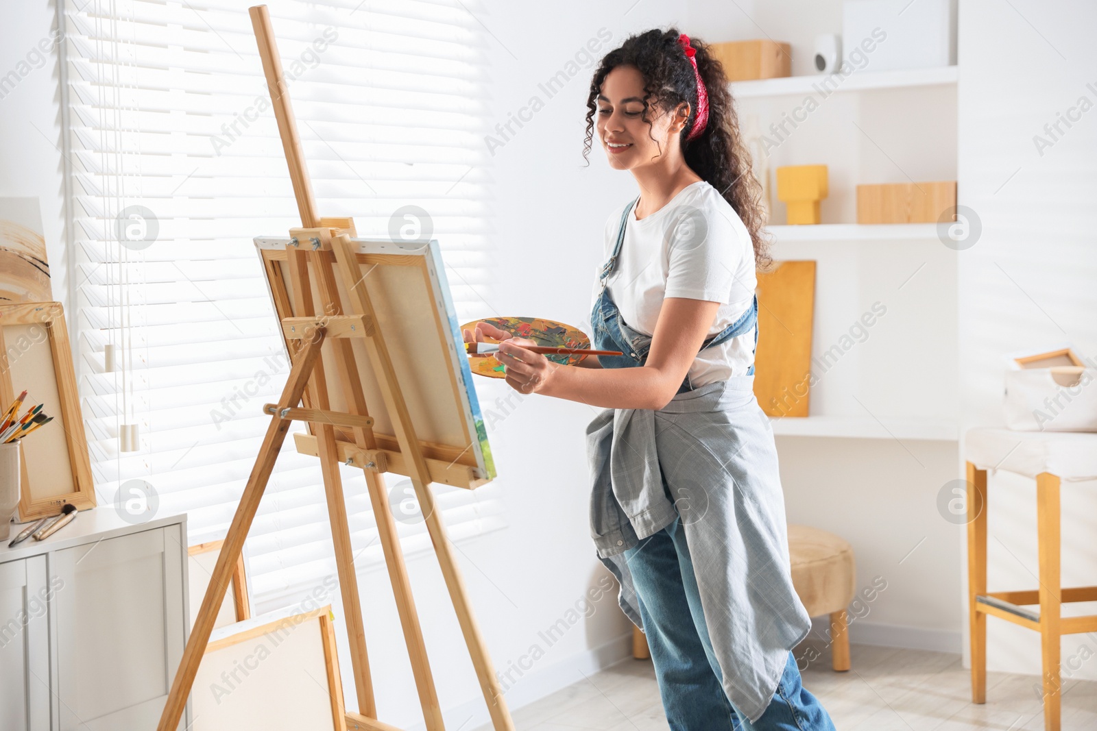 Photo of Smiling woman drawing picture on canvas in studio