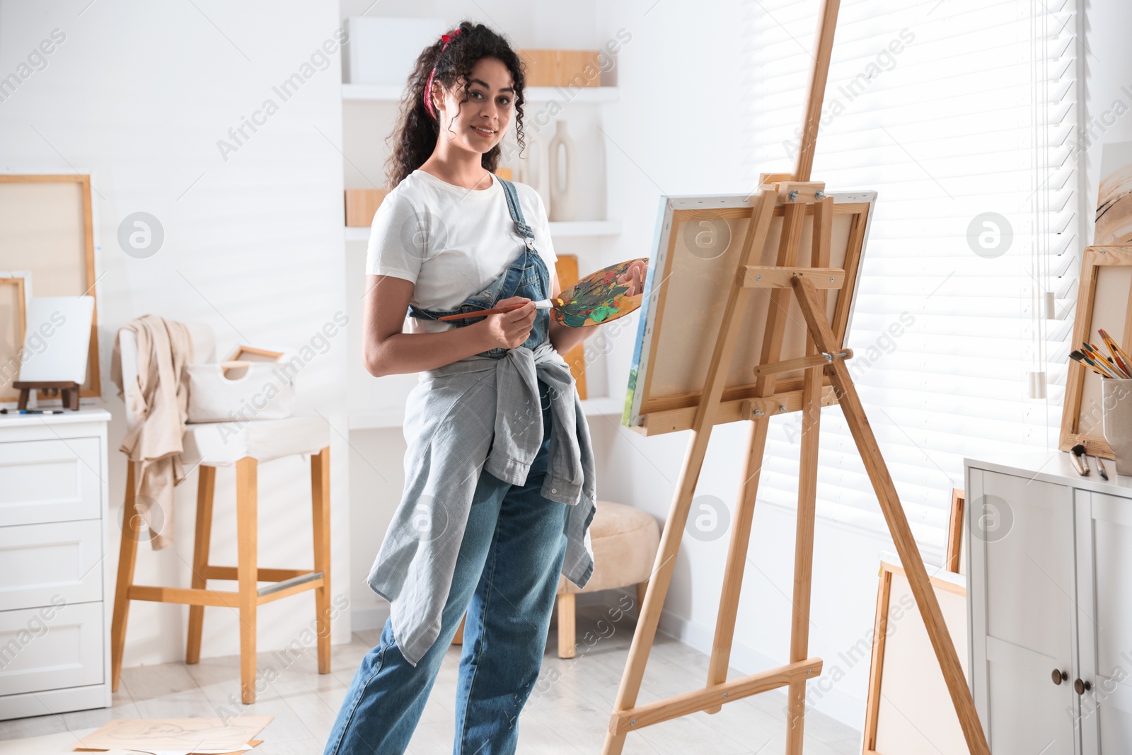 Photo of Smiling woman drawing picture on canvas in studio