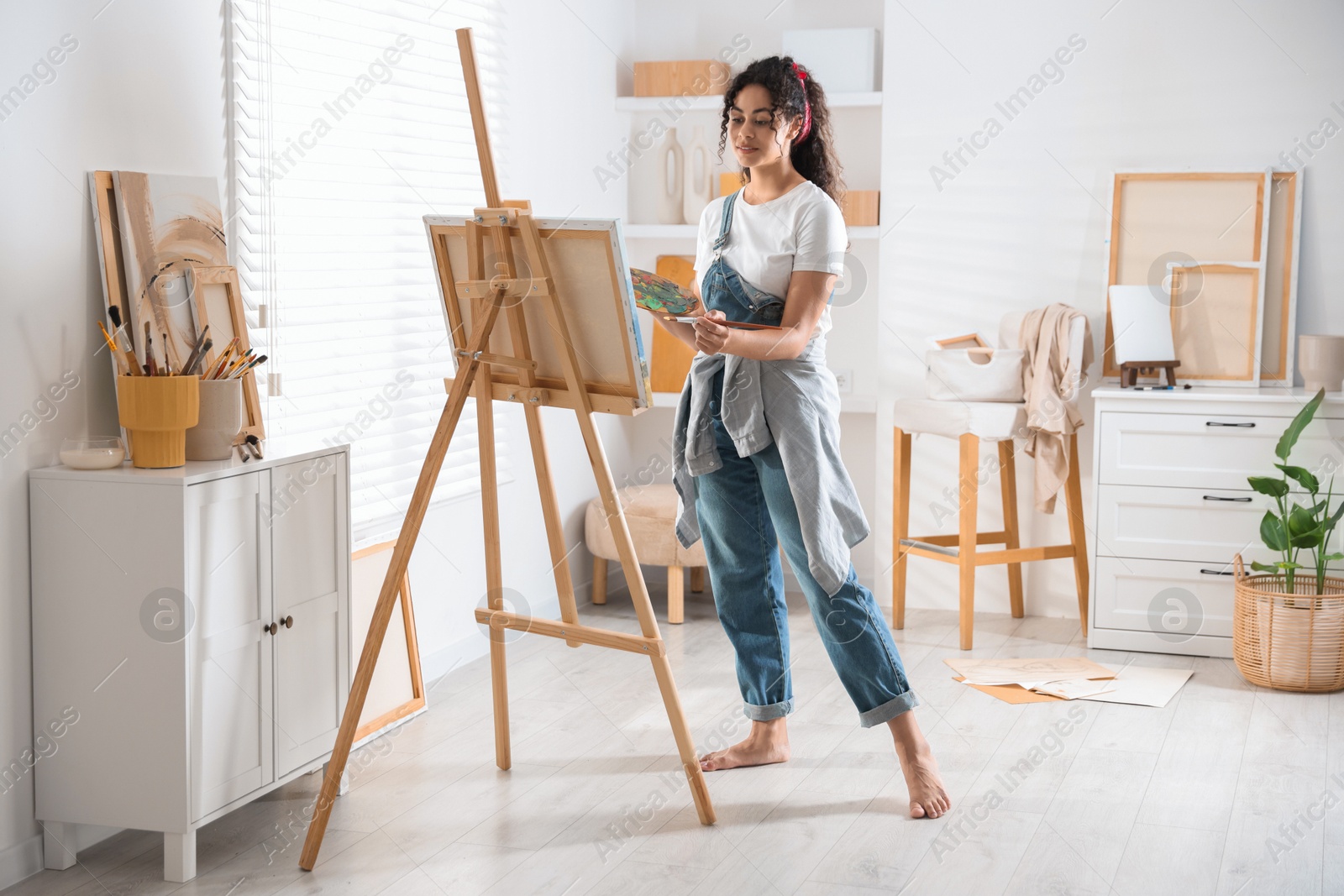 Photo of Beautiful woman drawing picture on canvas in studio