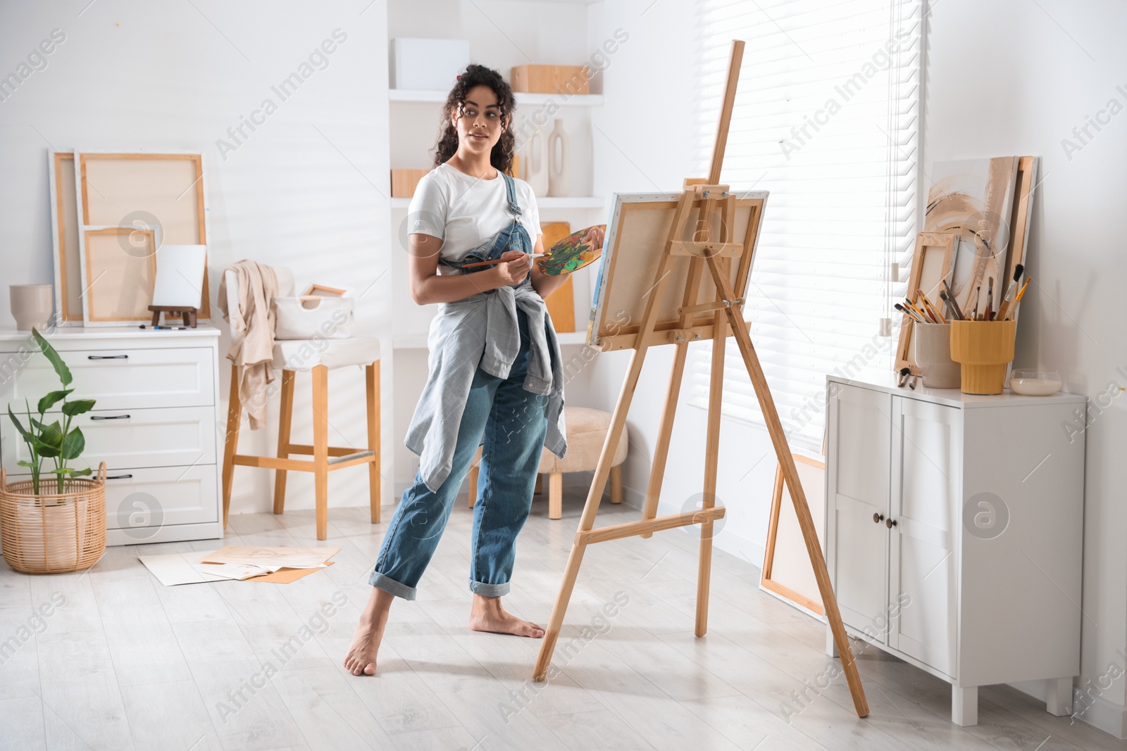 Photo of Beautiful woman drawing picture on canvas in studio