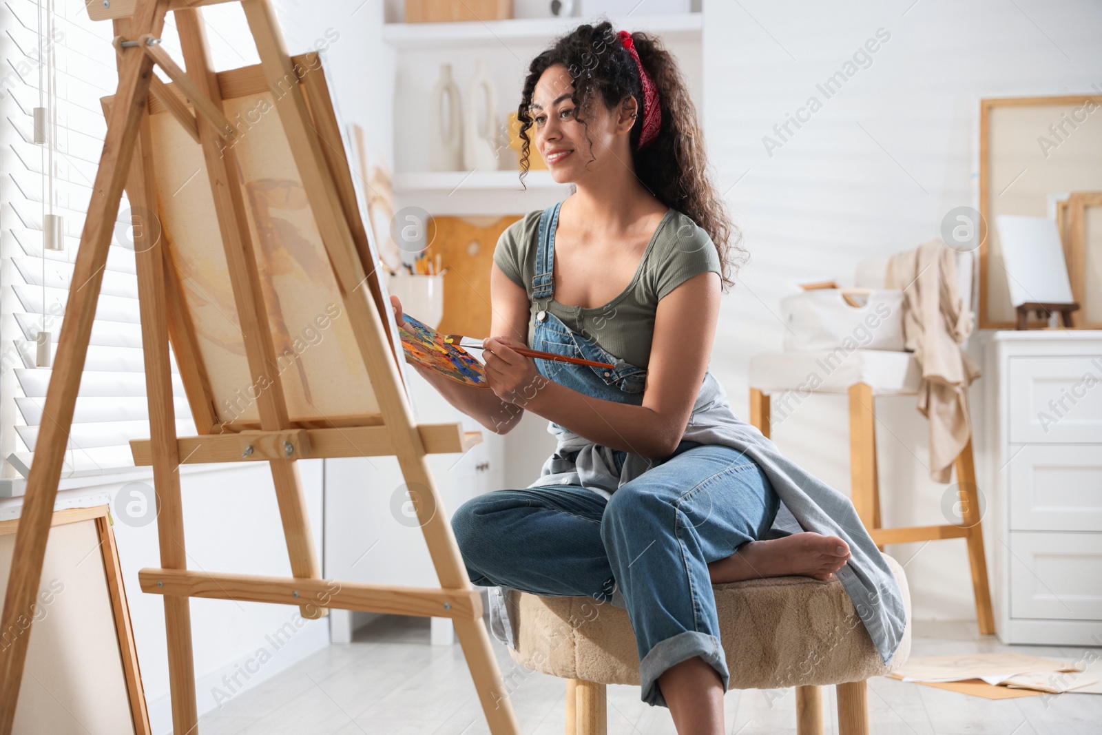 Photo of Smiling woman drawing picture on canvas in studio