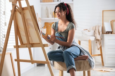 Photo of Smiling woman drawing picture on canvas in studio