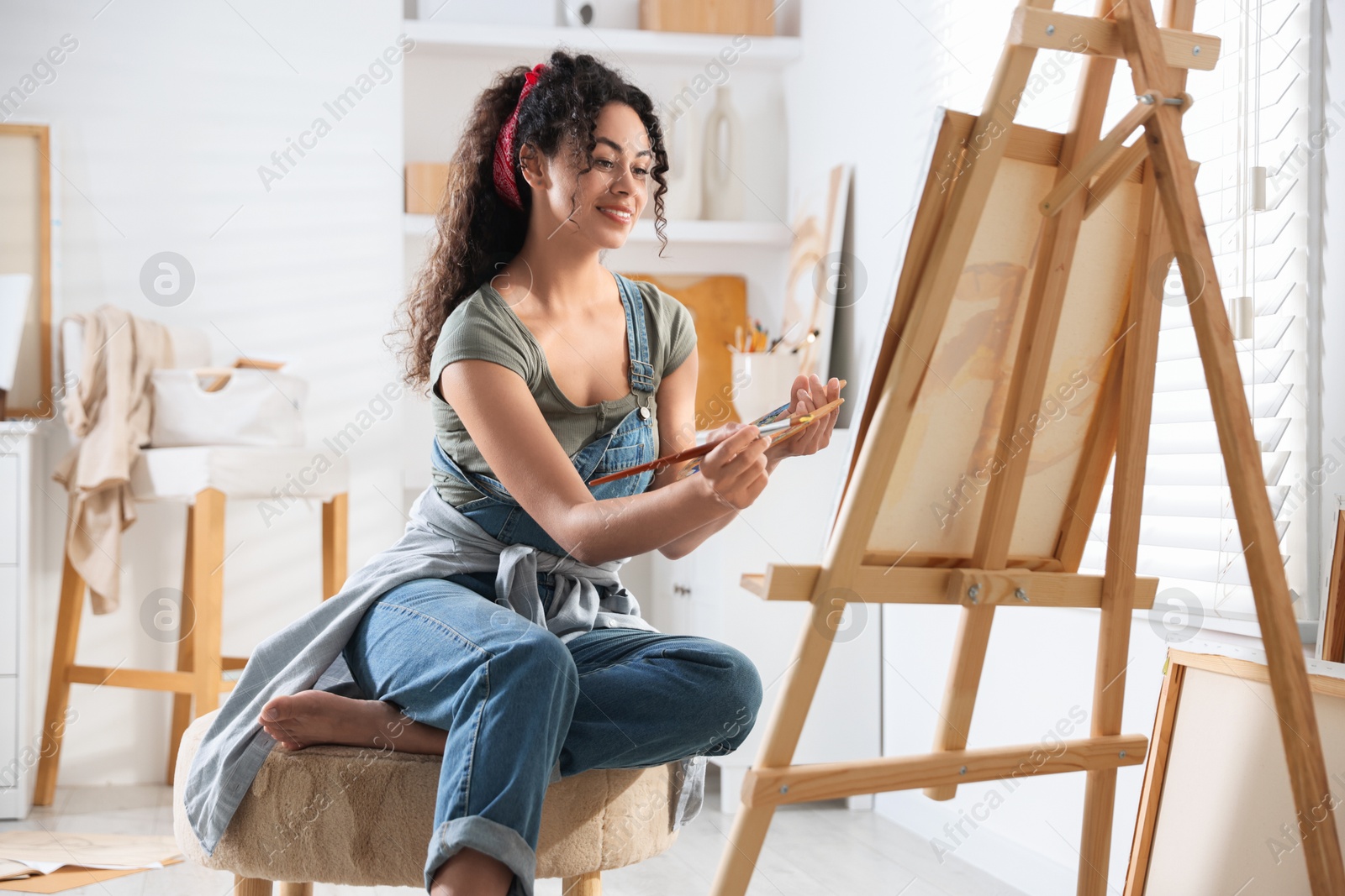 Photo of Smiling woman drawing picture on canvas in studio