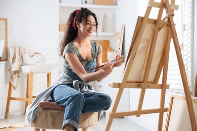 Smiling woman drawing picture on canvas in studio