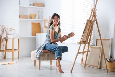 Smiling woman drawing picture on canvas in studio