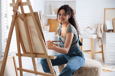 Smiling woman drawing picture on canvas in studio