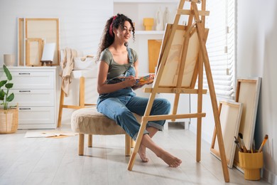 Smiling woman drawing picture on canvas in studio