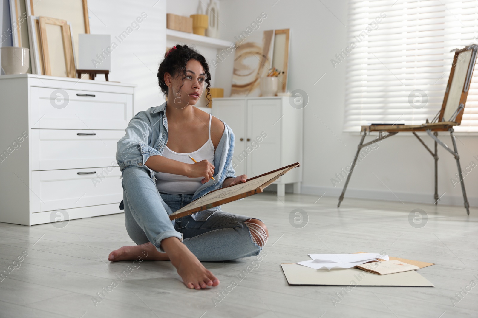 Photo of Woman drawing picture with pencil on floor in studio