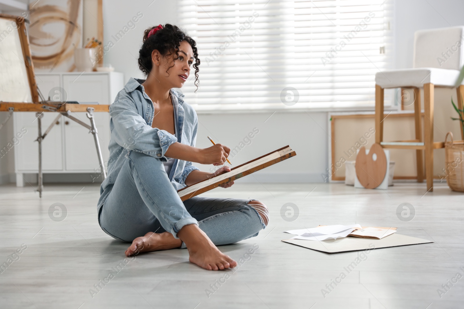 Photo of Woman drawing picture with pencil on floor in studio