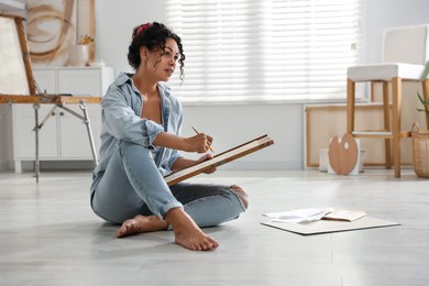 Photo of Woman drawing picture with pencil on floor in studio