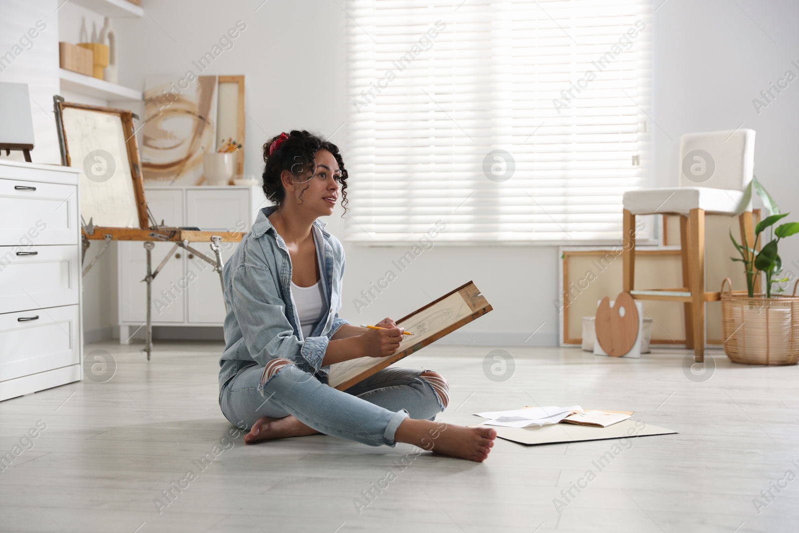 Photo of Woman drawing picture with pencil on floor in studio