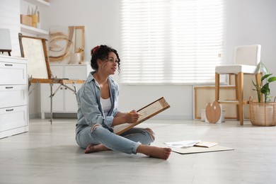 Photo of Woman drawing picture with pencil on floor in studio