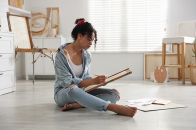 Woman drawing picture with pencil on floor in studio