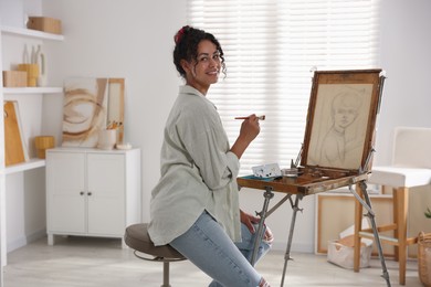 Smiling woman drawing picture on canvas in studio