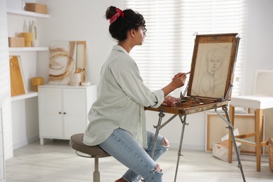 Beautiful woman drawing picture on canvas in studio