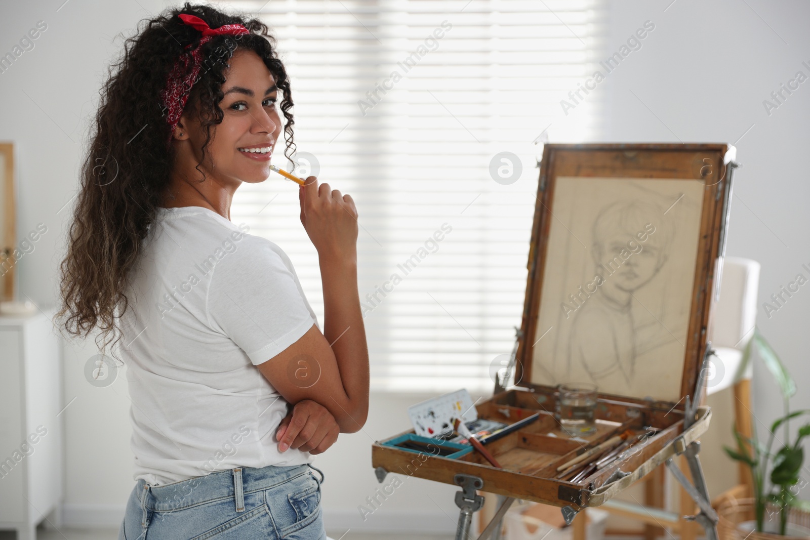 Photo of Smiling woman drawing picture with pencil in studio