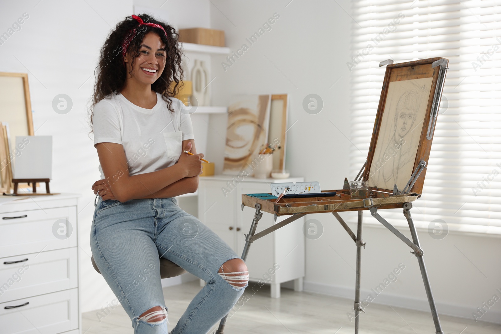 Photo of Smiling woman drawing picture with pencil in studio