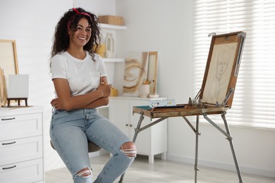 Smiling woman drawing picture with pencil in studio