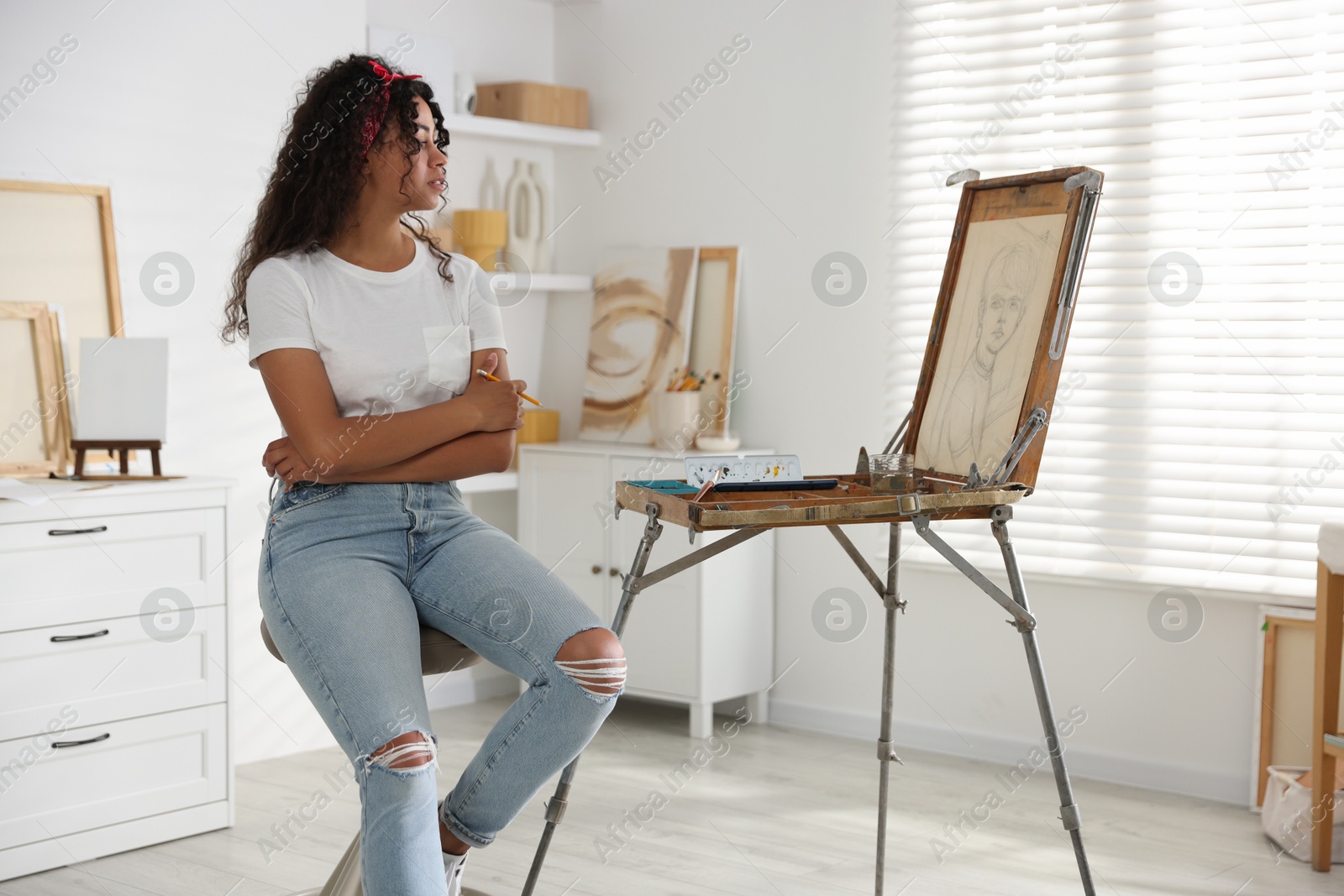 Photo of Beautiful woman sitting near picture in drawing studio