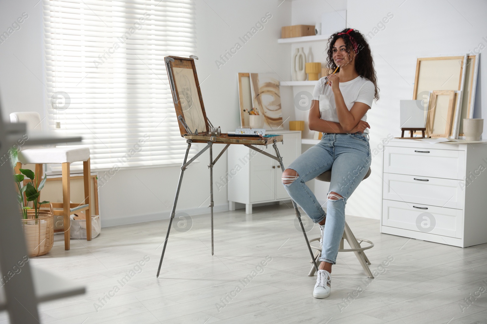 Photo of Happy woman drawing picture with pencil in studio