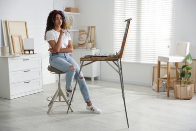 Beautiful woman sitting near picture in drawing studio