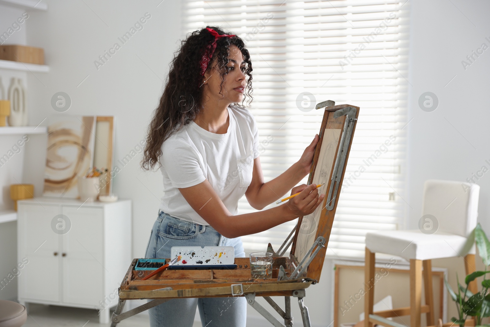 Photo of Beautiful woman drawing portrait with pencil in studio