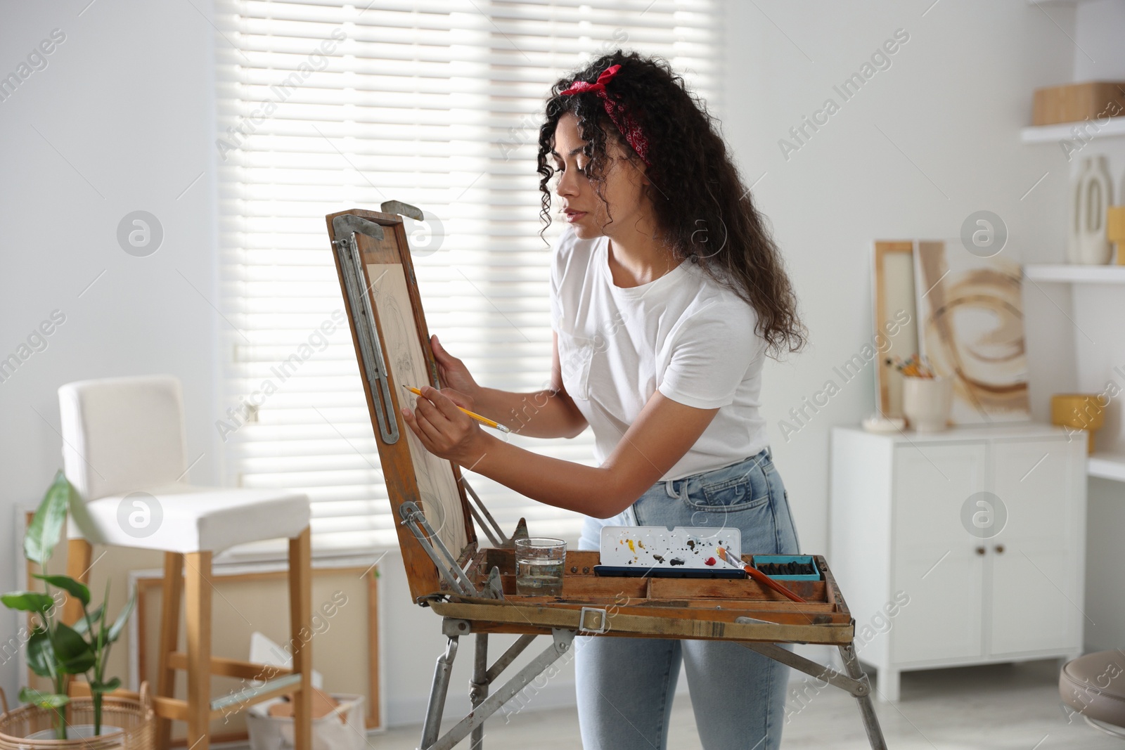 Photo of Beautiful woman drawing portrait with pencil in studio