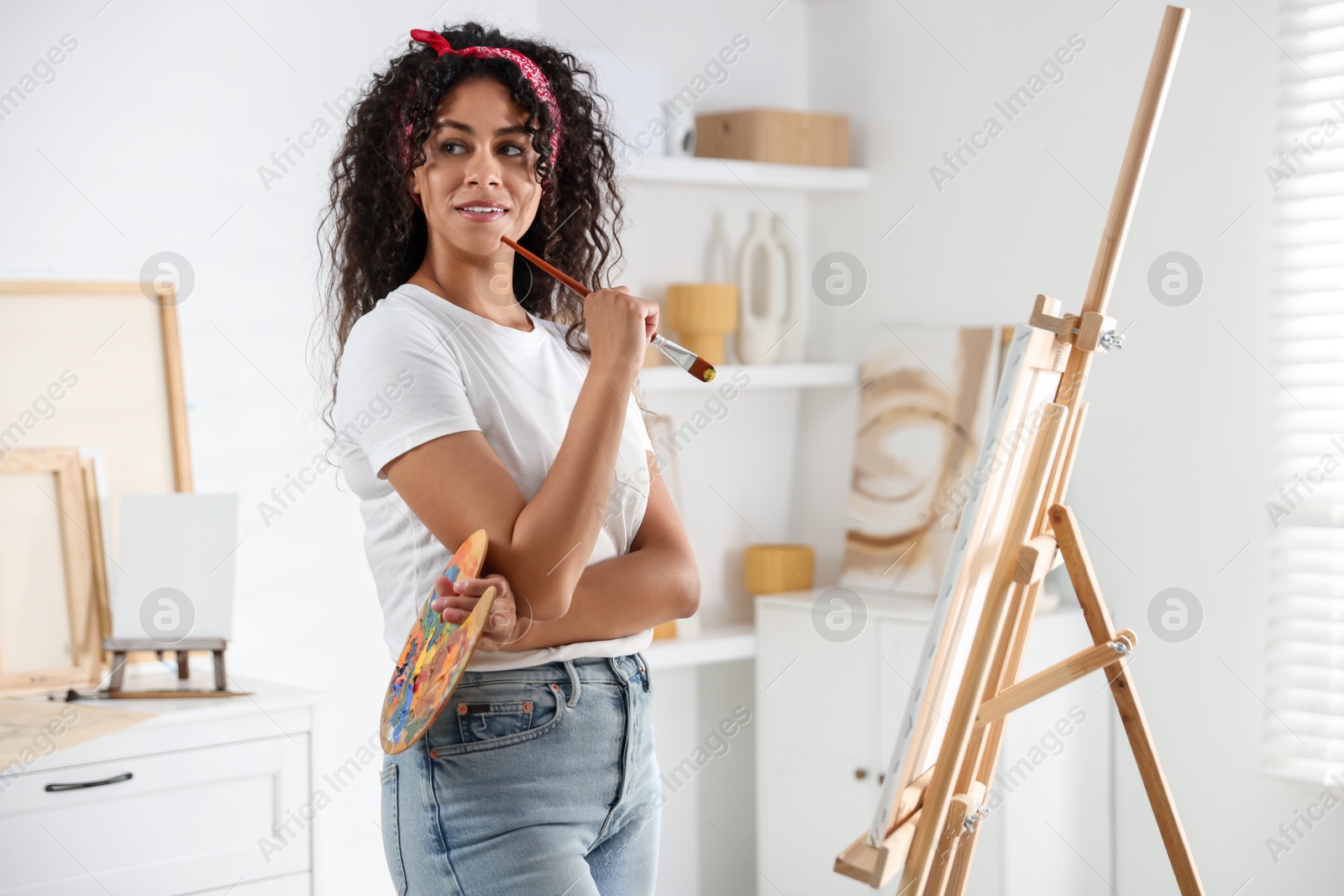 Photo of Smiling woman drawing picture on canvas in studio