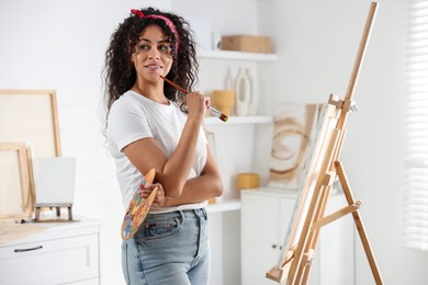 Smiling woman drawing picture on canvas in studio