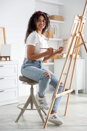 Smiling woman drawing picture on canvas in studio