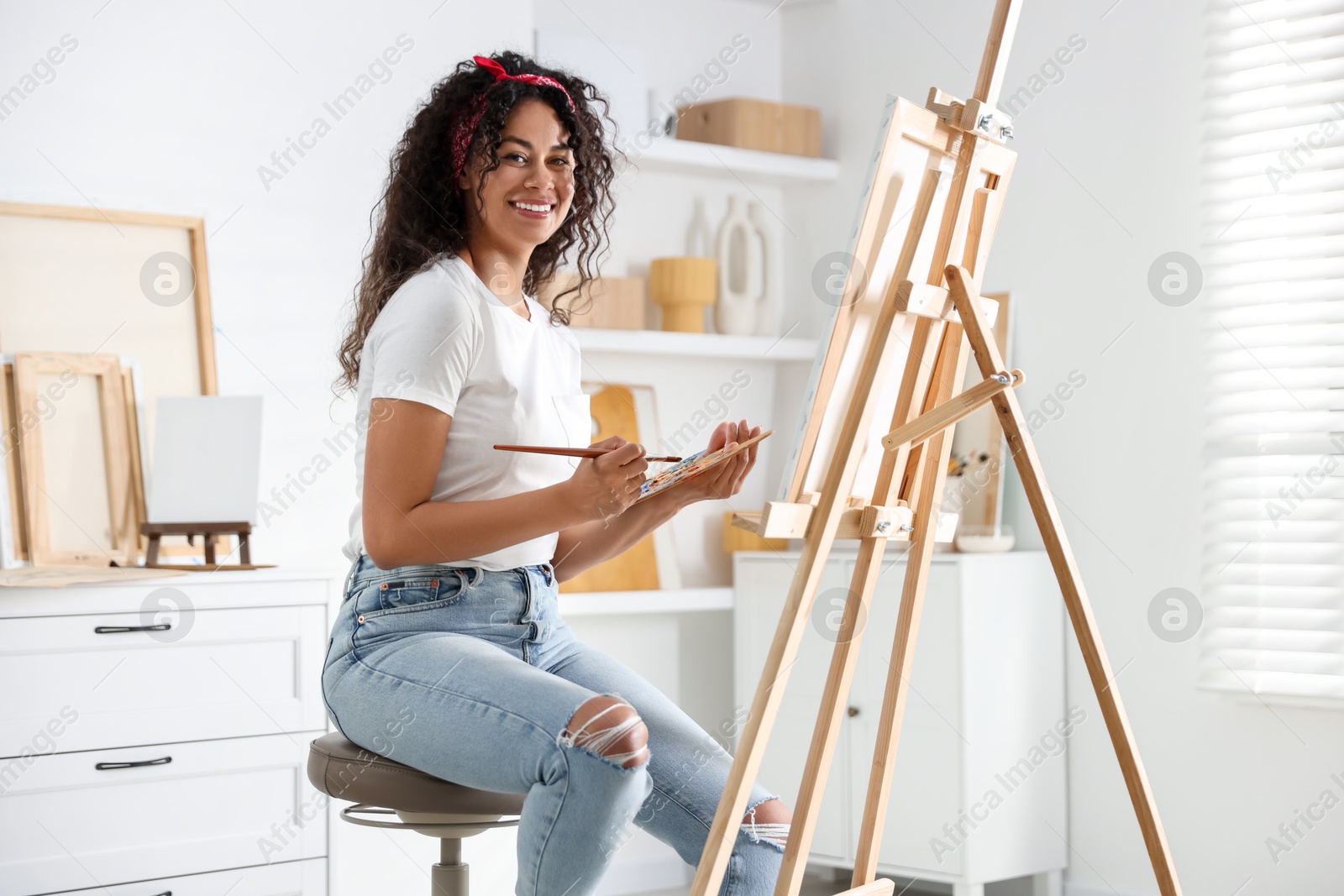 Photo of Smiling woman drawing picture on canvas in studio