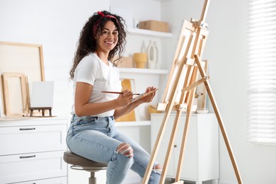 Smiling woman drawing picture on canvas in studio