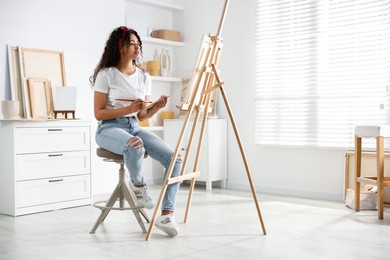 Beautiful woman drawing picture on canvas in studio