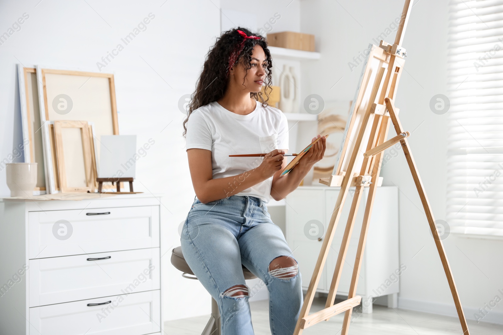 Photo of Beautiful woman drawing picture on canvas in studio