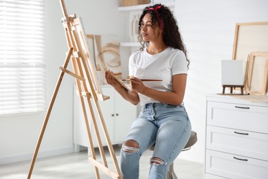 Beautiful woman drawing picture on canvas in studio