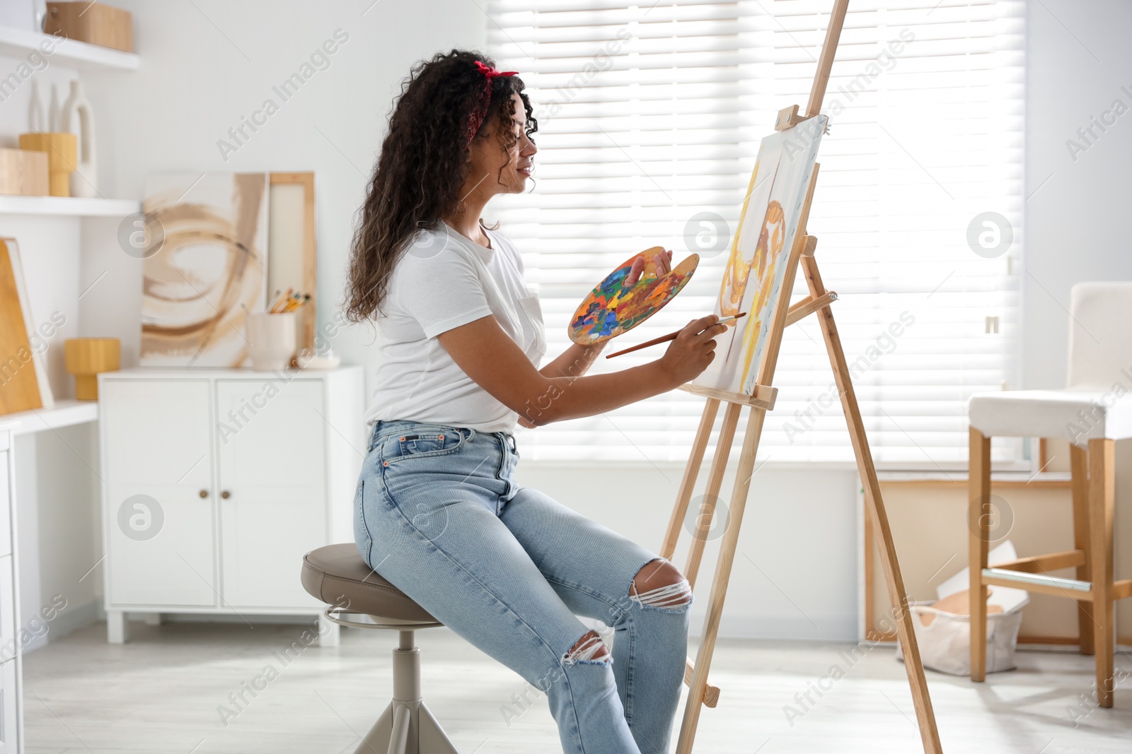 Photo of Beautiful woman drawing picture on canvas in studio