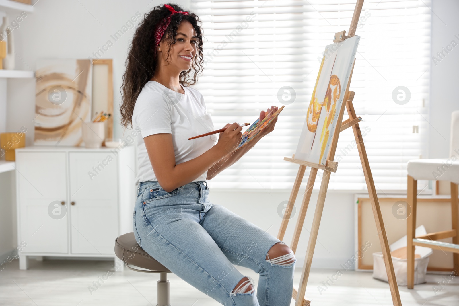 Photo of Smiling woman drawing picture on canvas in studio