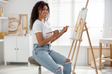 Smiling woman drawing picture on canvas in studio