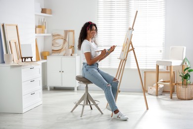 Smiling woman drawing picture on canvas in studio