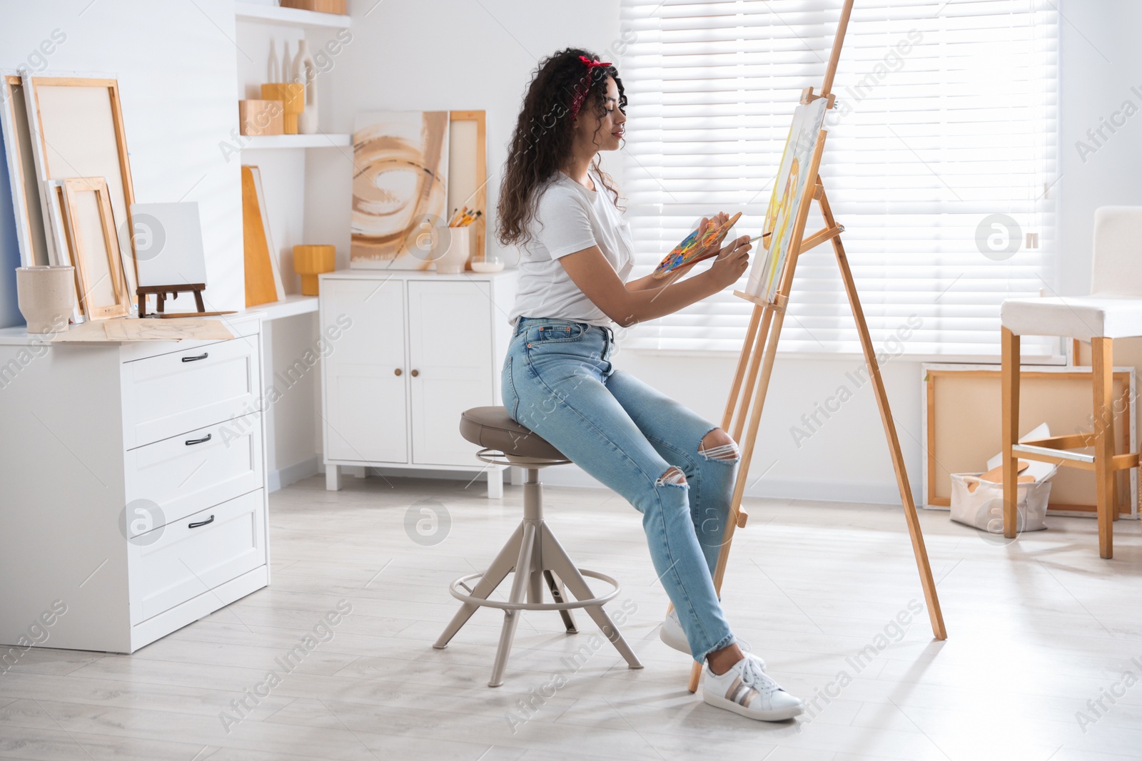 Photo of Beautiful woman drawing picture on canvas in studio