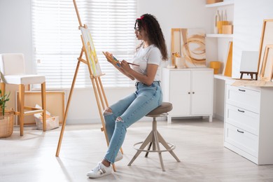 Photo of Beautiful woman drawing picture on canvas in studio