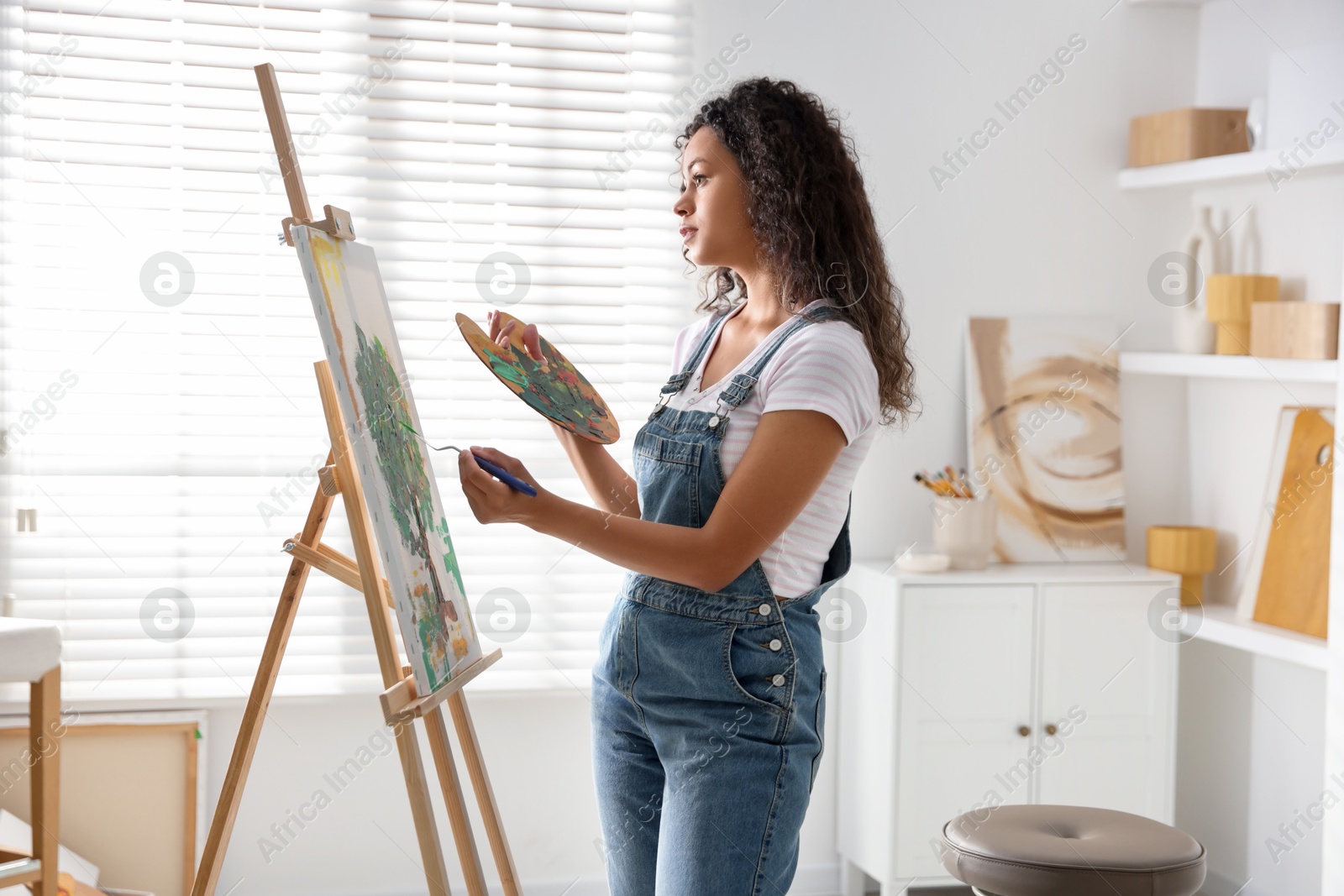 Photo of Beautiful woman drawing picture on canvas in studio