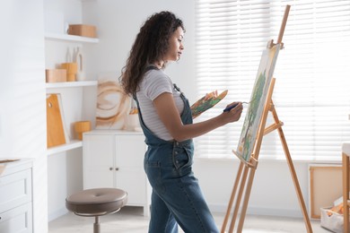 Beautiful woman drawing picture on canvas in studio