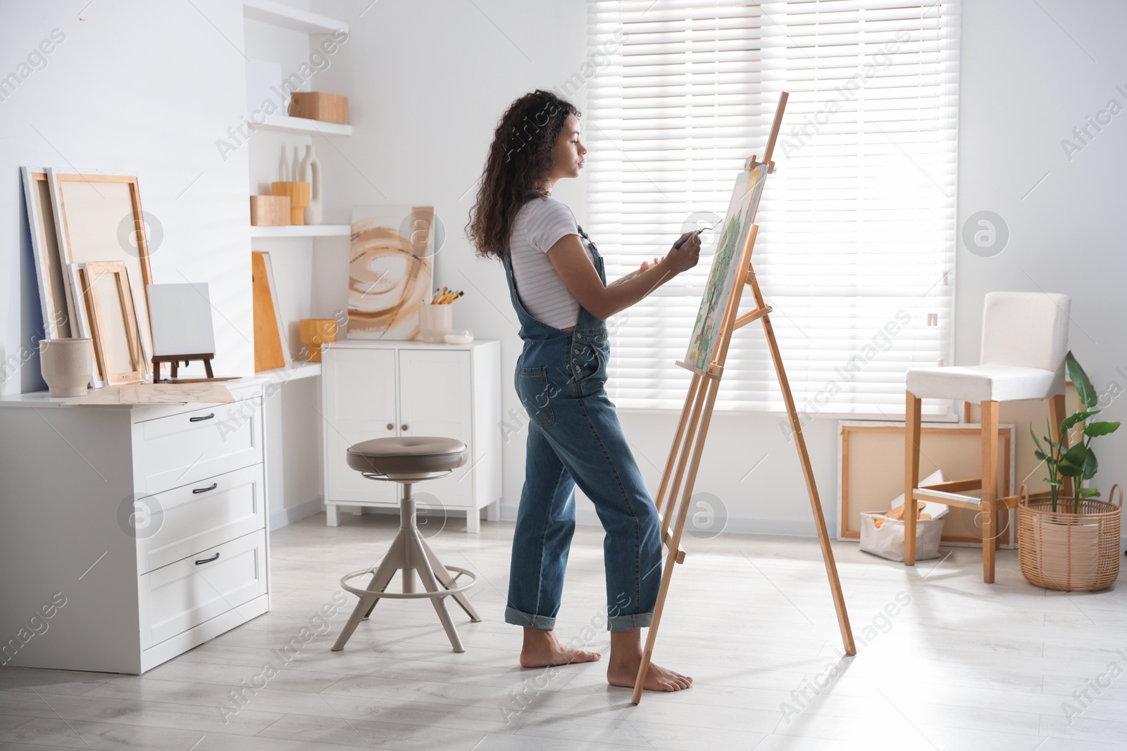 Photo of Beautiful woman drawing picture on canvas in studio