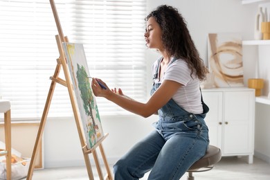 Beautiful woman drawing picture on canvas in studio